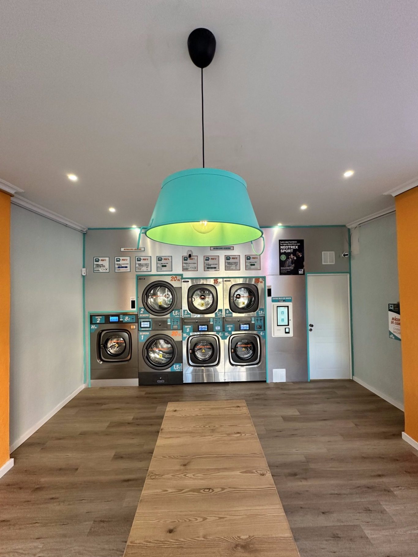 Interior de Lavandería Seco y Espuma Fuengirola con mesas, bancos y máquinas de lavandería. Luz tenue y decoración moderna.